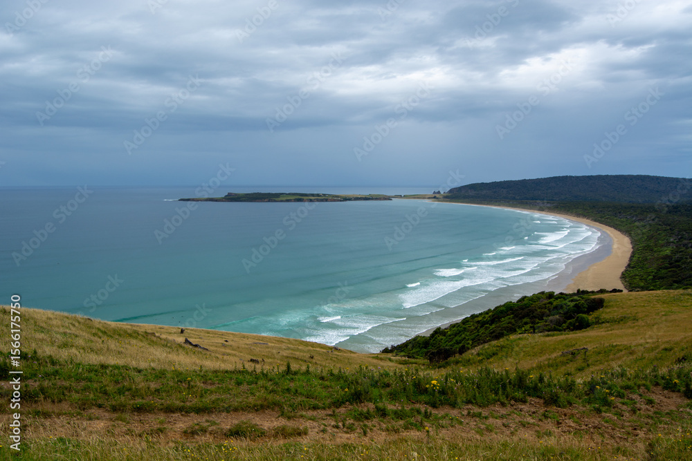 Obraz premium Scenic Coastal View with Gentle Waves and Green Hills