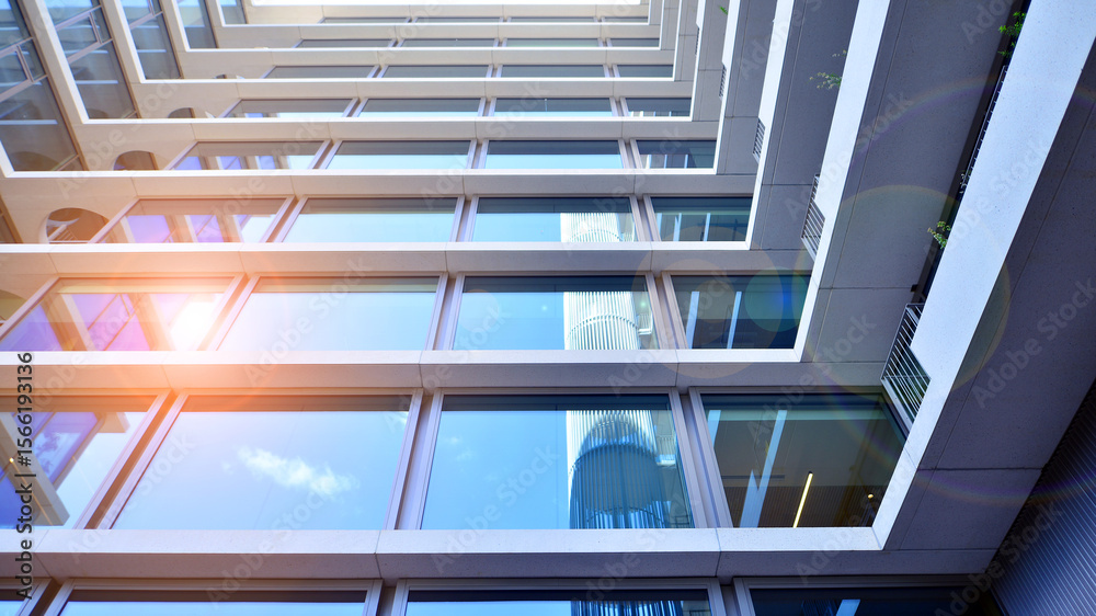 Obraz premium Modern office building with glass facade. Transparent glass wall of office building. Reflection of the blue sky on the facade of the building.