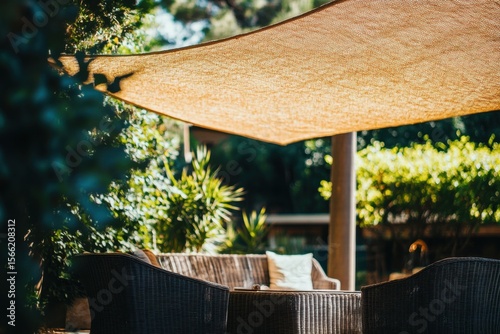 Sun shade creates a cozy outdoor space with garden furniture in a lush green setting, Low angle shot of a sun shade with garden furniture sitting outside a villa