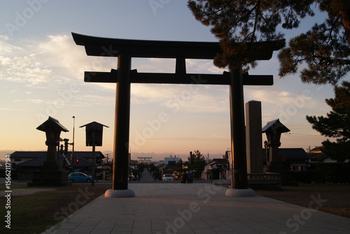 Foto 朝焼けに際立つ大鳥居と灯籠のシルエット