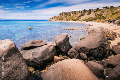 Fototapeta Naklejka Na Ścianę i Meble -  Breathtaking view of a rocky beach with crystal clear turquoise water, bathed in sunlight, showcasing the stunning coastal beauty