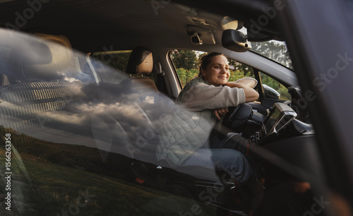 Happy young woman drivier looking out of car window, auto travel and adventure