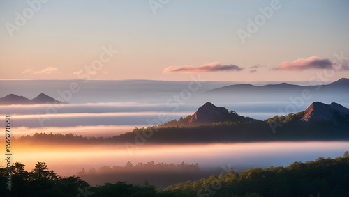 Misty mountain peaks glowing in the warm hues of an early morning sunrise.