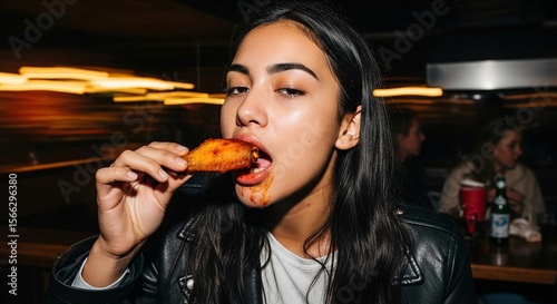 A 20 year old mixed race woman sweating eating extremely hot chicken wings. Sauce smeared around her mouth, motion blur, eat, messy, hunger, hungry, bbq, fried, fry, greasy, bite, biting, chew, young