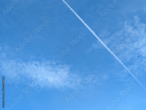 Blue Skies with wispy chemtrail aeroplane lines and fluffy white clouds