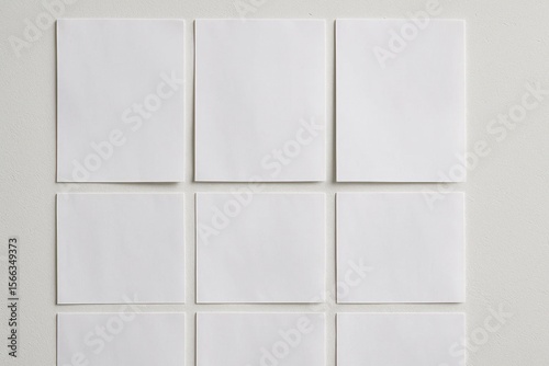 A collection of blank white paper sheets arranged neatly in a grid pattern on a light-colored background