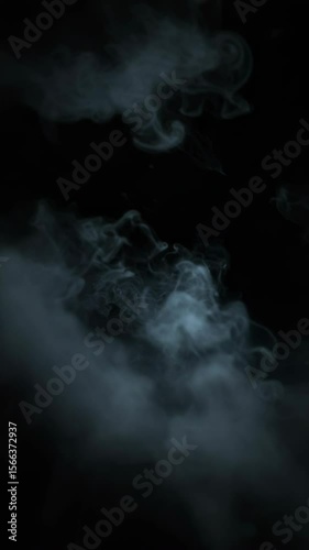 Dark smoke swirling in mysterious patterns against black background  