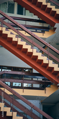 Diagonal view of multiple staircases forming zigzag pattern inside modern multi-story building. Structure, rhythm, repetition. Movement, elevation, functional aesthetic of contemporary urban design