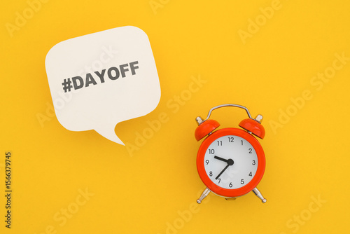 DAY OFF text on real white speech bubble paper cur with red analog alarm clock on yellow background