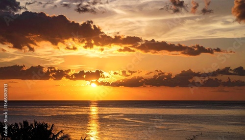 Spectacular Sunset over Calm Ocean Golden Hues and Dramatic Clouds