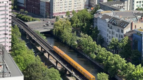 Aerial view of a yellow u-bahn train on an  elevated train track running through a Berlin Kreuzberg cityscape