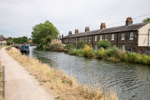 Foto View along the towpath of the River Lea Navigation with houses at Government Row visible across the water on the right, capturing a quiet canalside scene