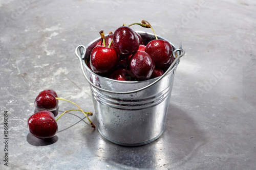 Cherries in a metal containerl with water drops close up on a vintage background