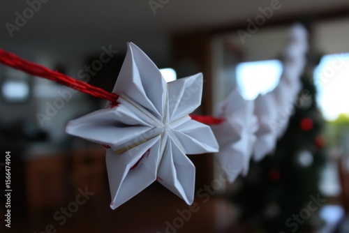 A white origami star hanging from a red string
