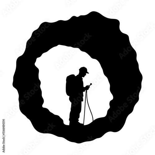 Silhouette of a hiker checking his GPS device in a cave  