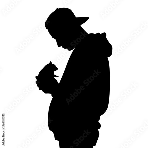 Young man holding a small pet while standing in silhouette  