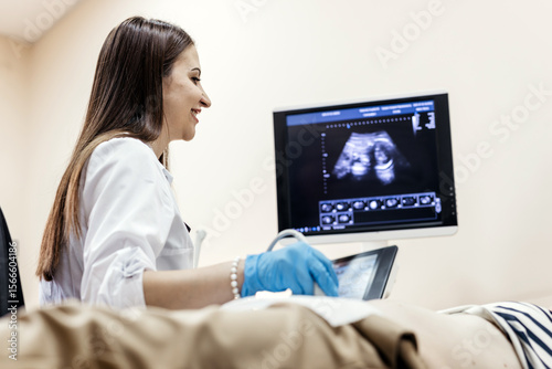 Young pregnant woman undergoing ultrasound diagnosis at clinic. Concept early pregnancy monitoring and fetal health