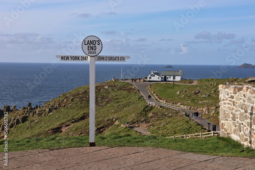Iconic Land's End signpost with distance to New York and John O’Groats displayed; coastal view of the rocky Cornish coastline and Atlantic Ocean