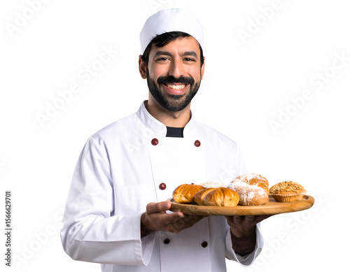 A friendly baker in a crisp white uniform beams while presenting a tempting tray of assorted baked delights.