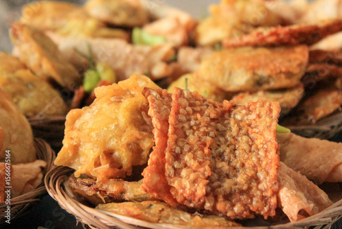 Close-up of several woven baskets filled with a variety of deep-fried Indonesian snacks, including fried tempeh and fried tahu, showing a spread of traditional street food, related to food culture