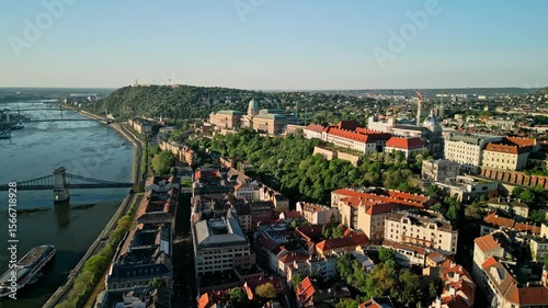 Aerial sunrise video from Fisherman's Bastion with sideward drone motion, keeping Buda Castle centered while revealing rooftops and historic architecture of Budapest’s Castle District.  