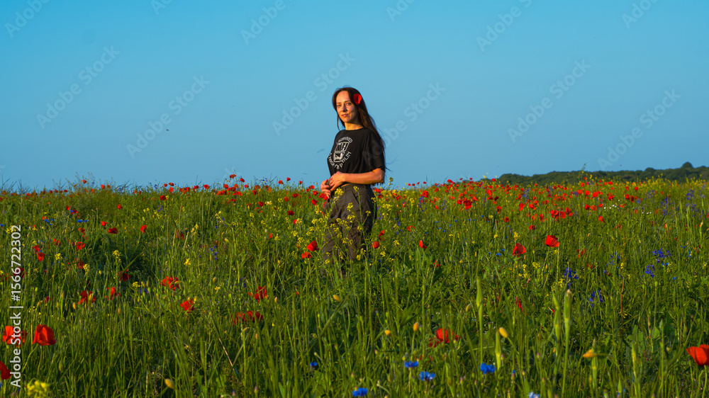 A young woman with long dark hair sitting on a green meadow in summer, surrounded by tall grass and wildflowers, enjoying the warm golden sunlight. A young woman with long dark hair sitting on a green meadow in summer, surrounded by tall grass and wildflowers, enjoying the warm golden sunlight.