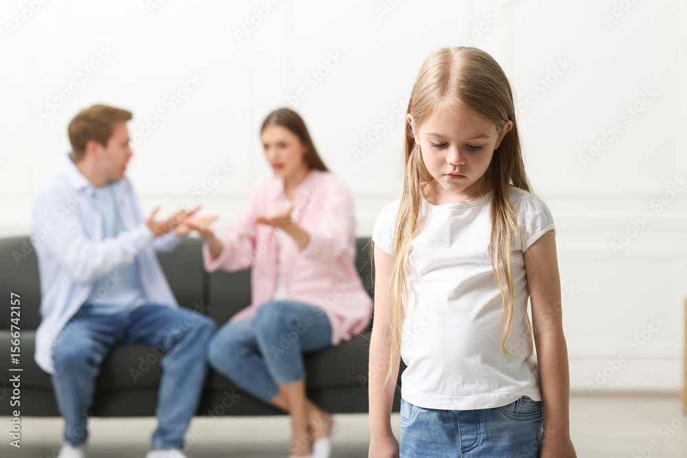 Fototapeta premium Upset little girl and her parents fighting at home, selective focus