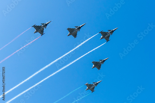 Five gray fighter jets with red white green colors in the blue sky