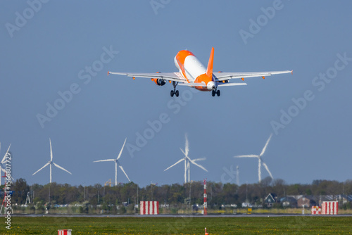 Obraz na plátně EasyJet Airbus A320 taking off from Amsterdam Airport Schiphol with wind turbine