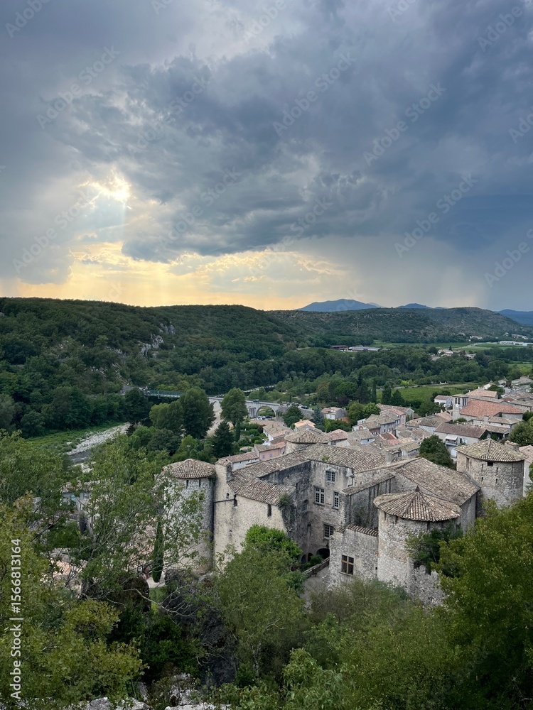 Obraz premium Scenic view of a historic village surrounded by lush greenery and dramatic skies in the evening