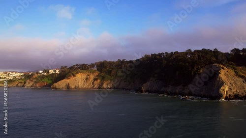 Stunning 4K aerial drone footage of the Golden Gate Bridge in San Francisco, California. Shot during sunset with low evening fog rolling over the bridge, capturing the iconic red structure