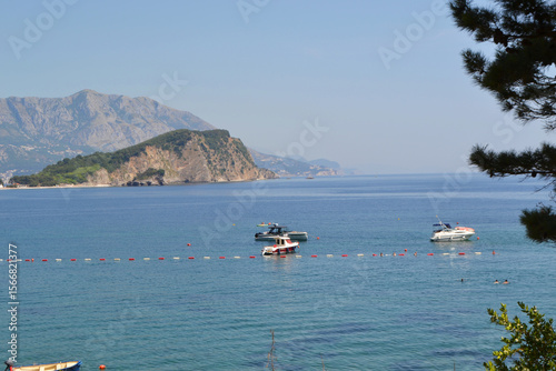 Picturesque Mogren Beach in Budva, Montenegro, with Sunbeds, Umbrellas, and Sveti Nikola Island View