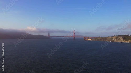 Stunning 4K aerial drone footage of the Golden Gate Bridge in San Francisco, California. Shot during sunset with low evening fog rolling over the bridge, capturing the iconic red structure