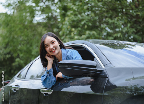 Portrait of a happy asian woman driving a car on a road trip