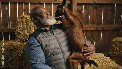 Bearded African American man hugs goat in barn with hay, rural farming, animal care and friendship, countryside lifestyle