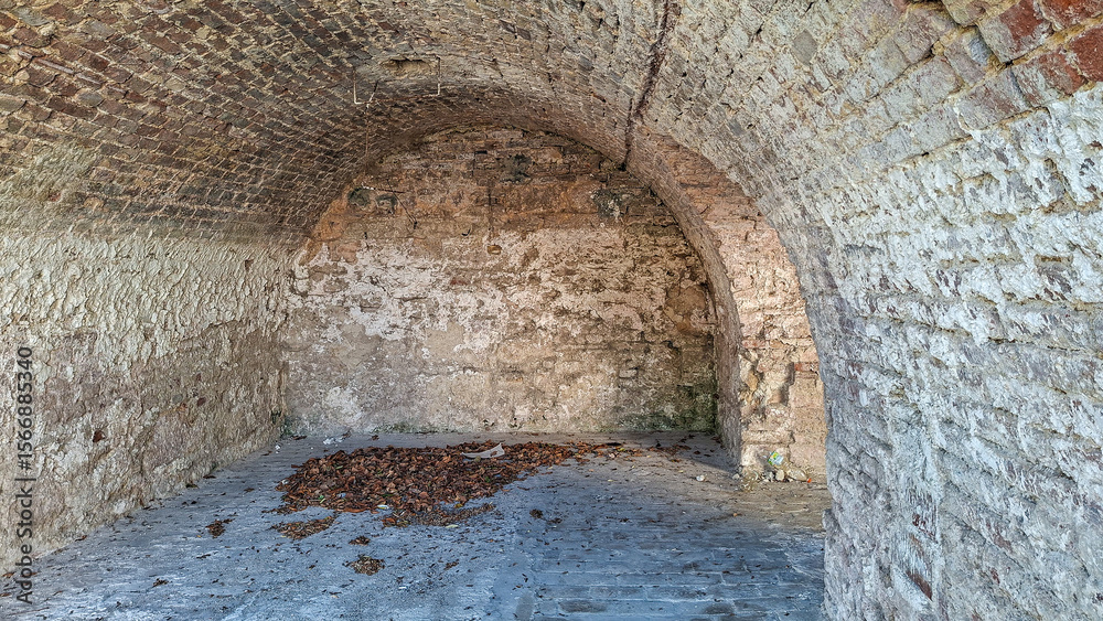 Obraz premium Ancient Brick Arched Structure with Weathered Surface and Fallen Leaves