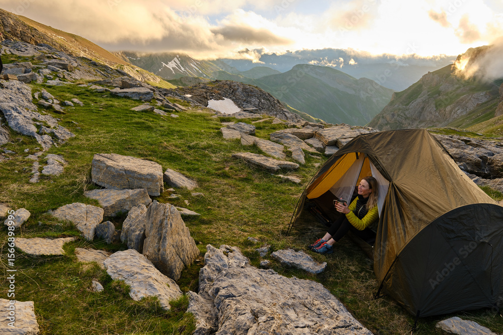 Fototapeta premium Woman sitting in a tent holding a cup of coffee in her hands