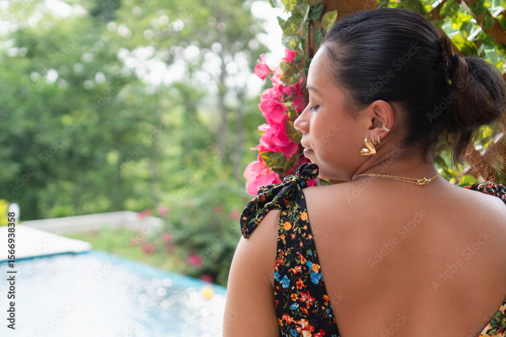 Fashion model posing near pink flowers with swimming pool in background Fashion model posing near pink flowers with swimming pool in background
