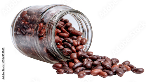 A glass jar filled with assorted brown beans spilling onto a white surface.
