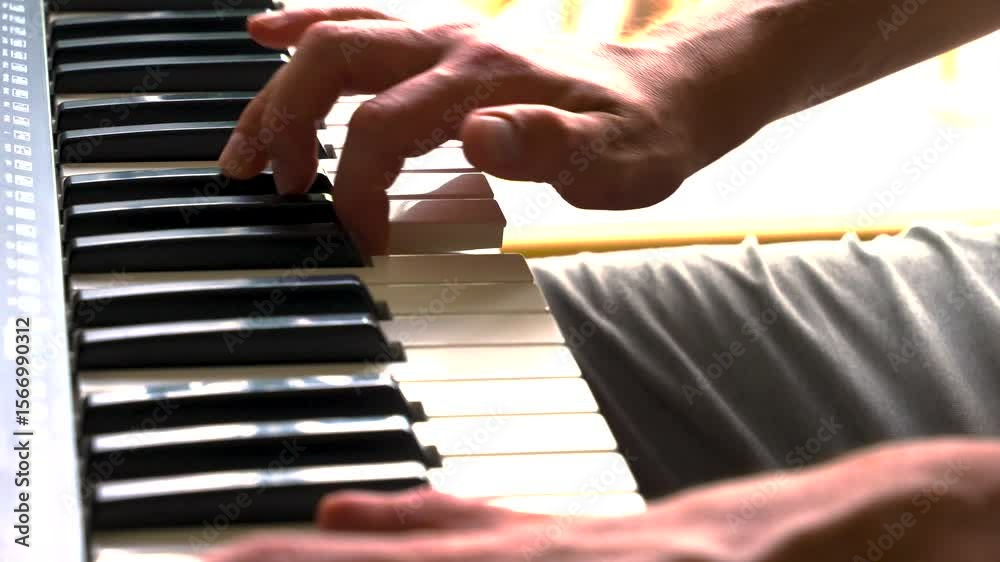 Male pianist's hands move gracefully across a black and white piano keyboard in a bright, sunlit studio by a window, demonstrating precise finger technique and chord transitions in a smooth, steady sl