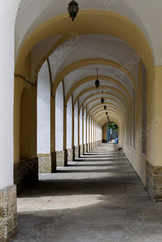 Long shaded passageway with repeating arches and hanging lanterns in Saint Petersburg, creating a rhythmic pattern of light and shadow.