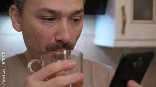 Reflective man sips a drink, absorbed in thoughts about evening plans and relaxation, blending themes of lifestyle and technology while highlighting contemporary living with devices and leisure