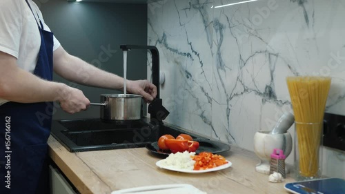 Skilled chef fills a pot with tap water, cooks colorful vegetables and boils pasta on a modern countertop, demonstrating culinary skill and dedication to fresh