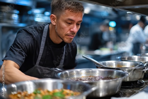 A skilled chef carefully watches over multiple sauce pans, ensuring the flavors blend perfectly, reflecting dedication and expertise in culinary art presented in the kitchen.
