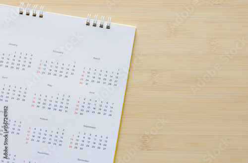 close up top view on white calendar 12 month to make schedule and appointment meeting or manage timetable each day lay on wood table background for planning work and life concept