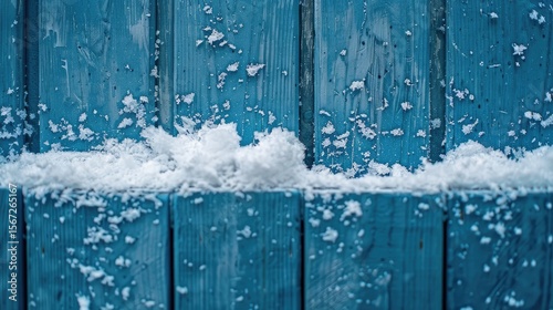 A close-up of snow resting on a blue wooden surface.