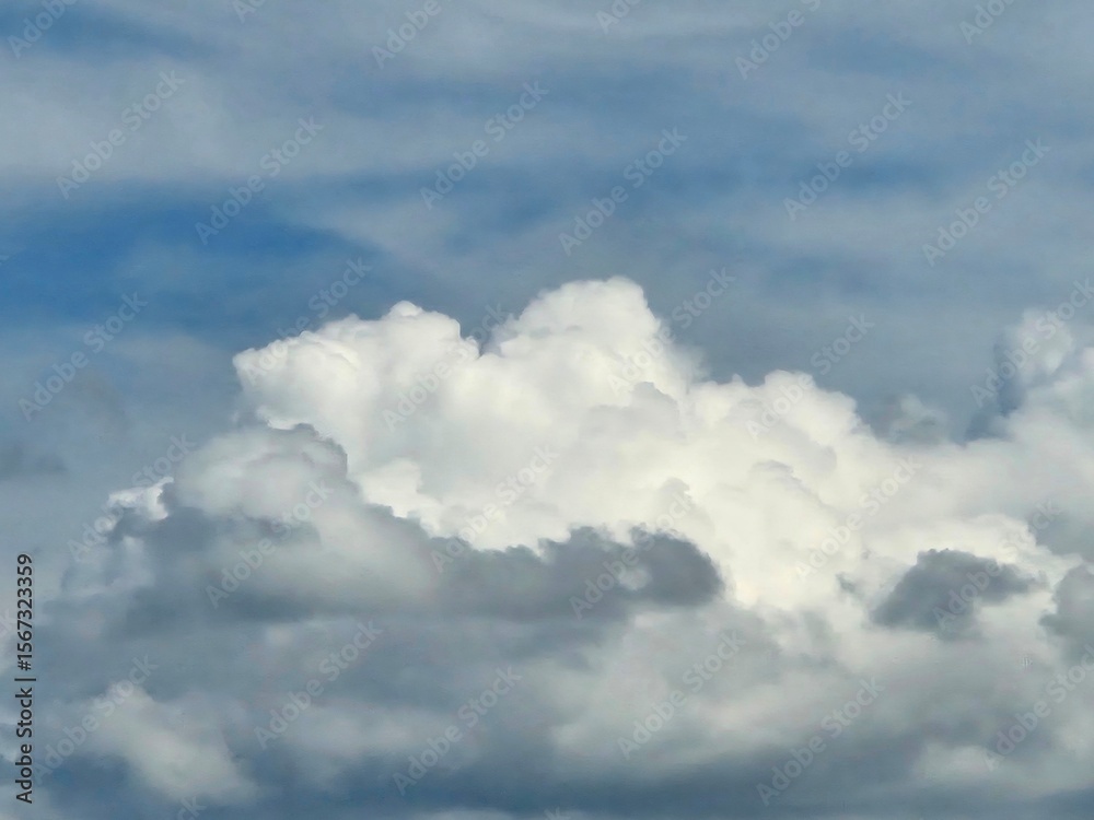 Obraz premium Towering cumulus cloud formation rising against a bright blue sky on a clear day