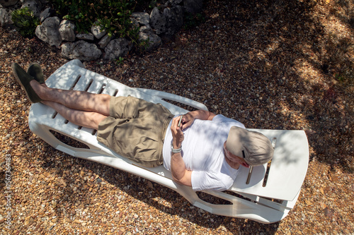 Relaxing Outdoors on a Lounger with a Mobile Phone in Hand