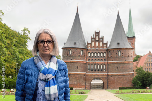 Senior Woman Posing in Front of Historic Landmark with Brick Architecture
