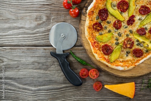Pizza on by cutter on wooden table